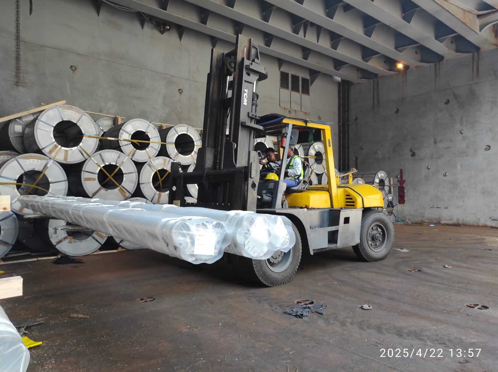 Forklift operation handling steel coils and packaged materials with precision inside the vessel